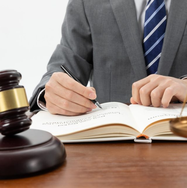 closeup-shot-person-writing-book-with-gavel-table (1)